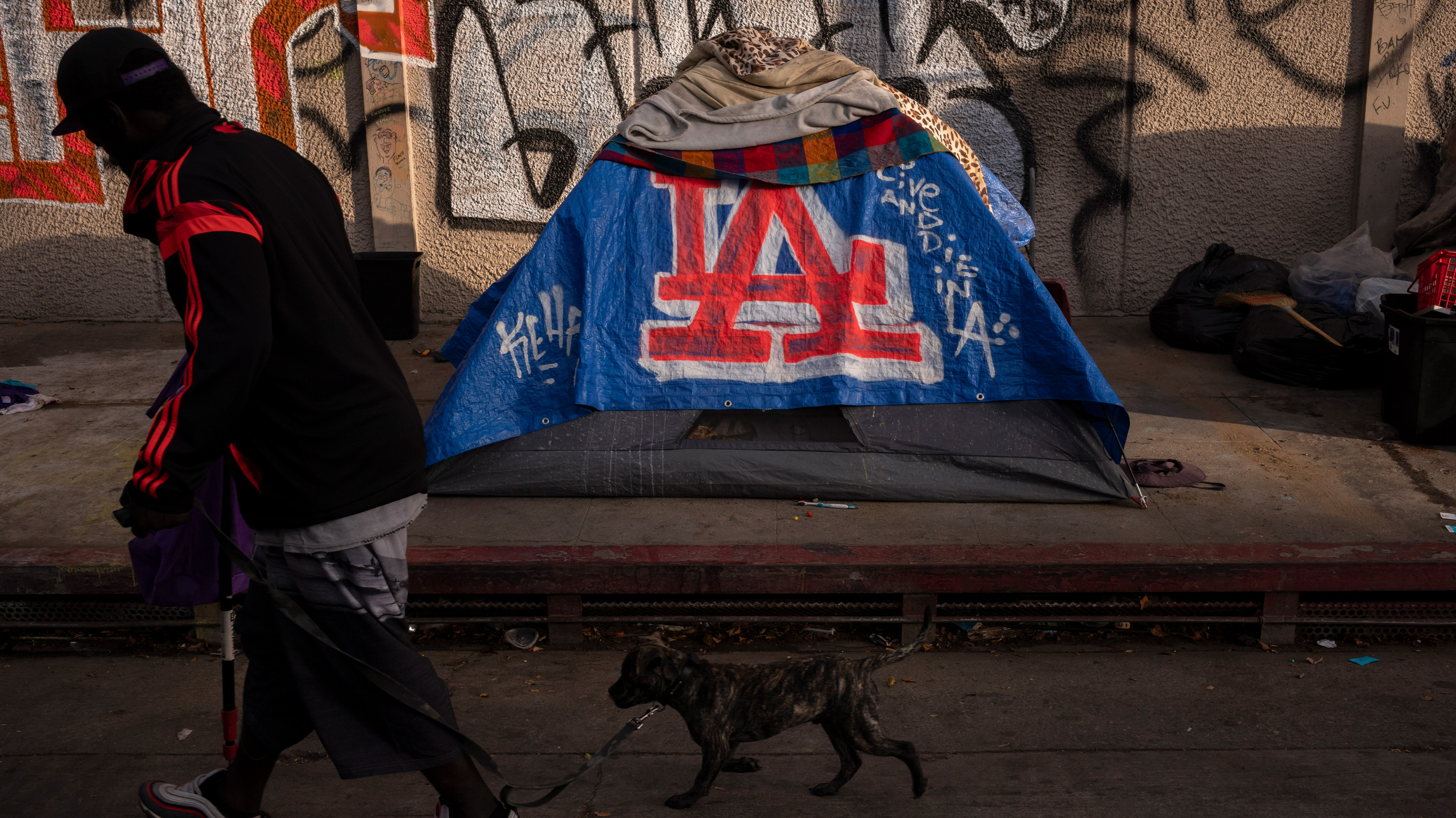 FILE - A man walks past a homeless encampment in downtown Los Angeles, Wednesday, Oct. 25, 2023. 