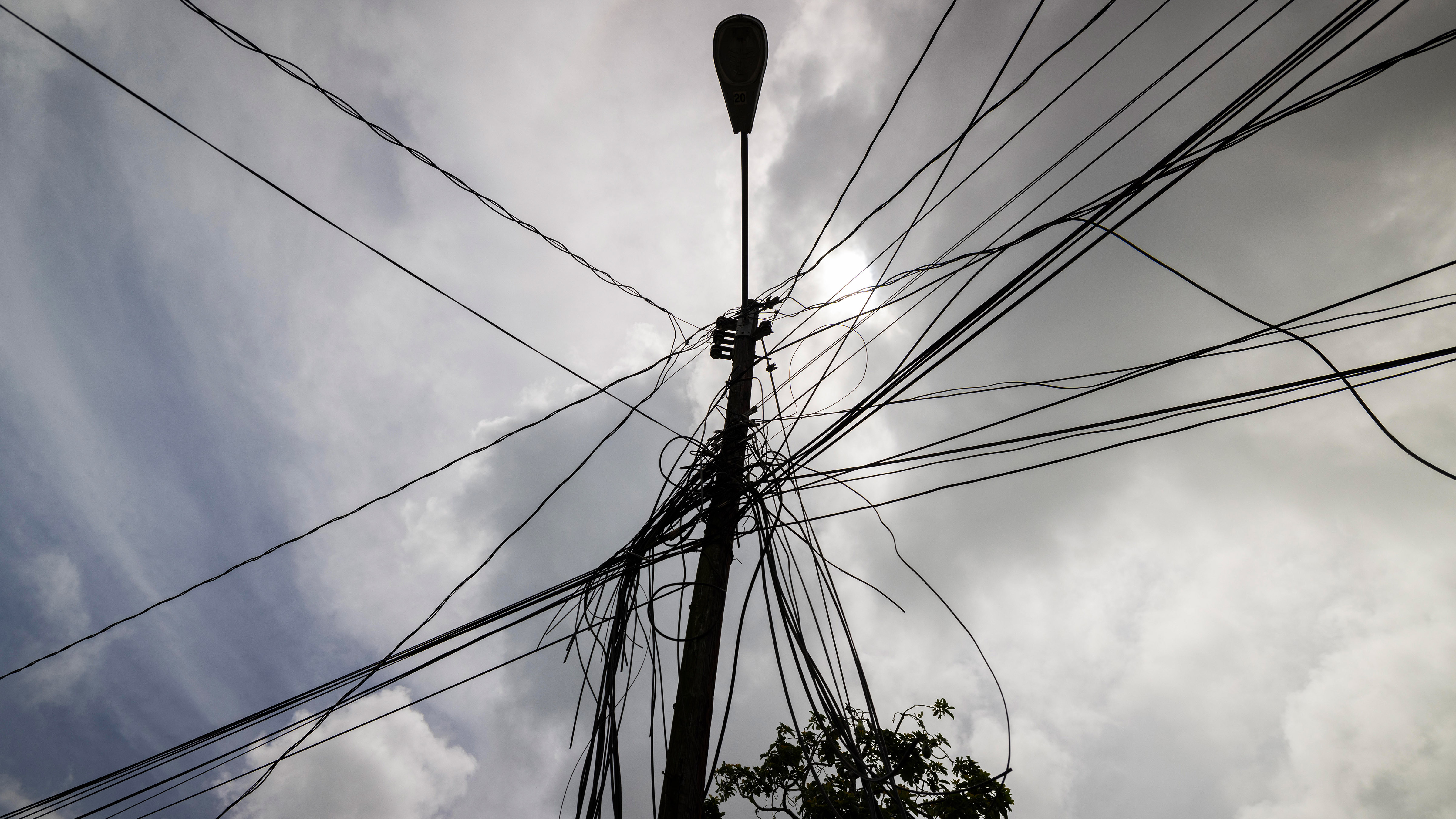 A utility pole with loose cables towers over a home in Loiza, Puerto Rico, Sept. 15, 2022.